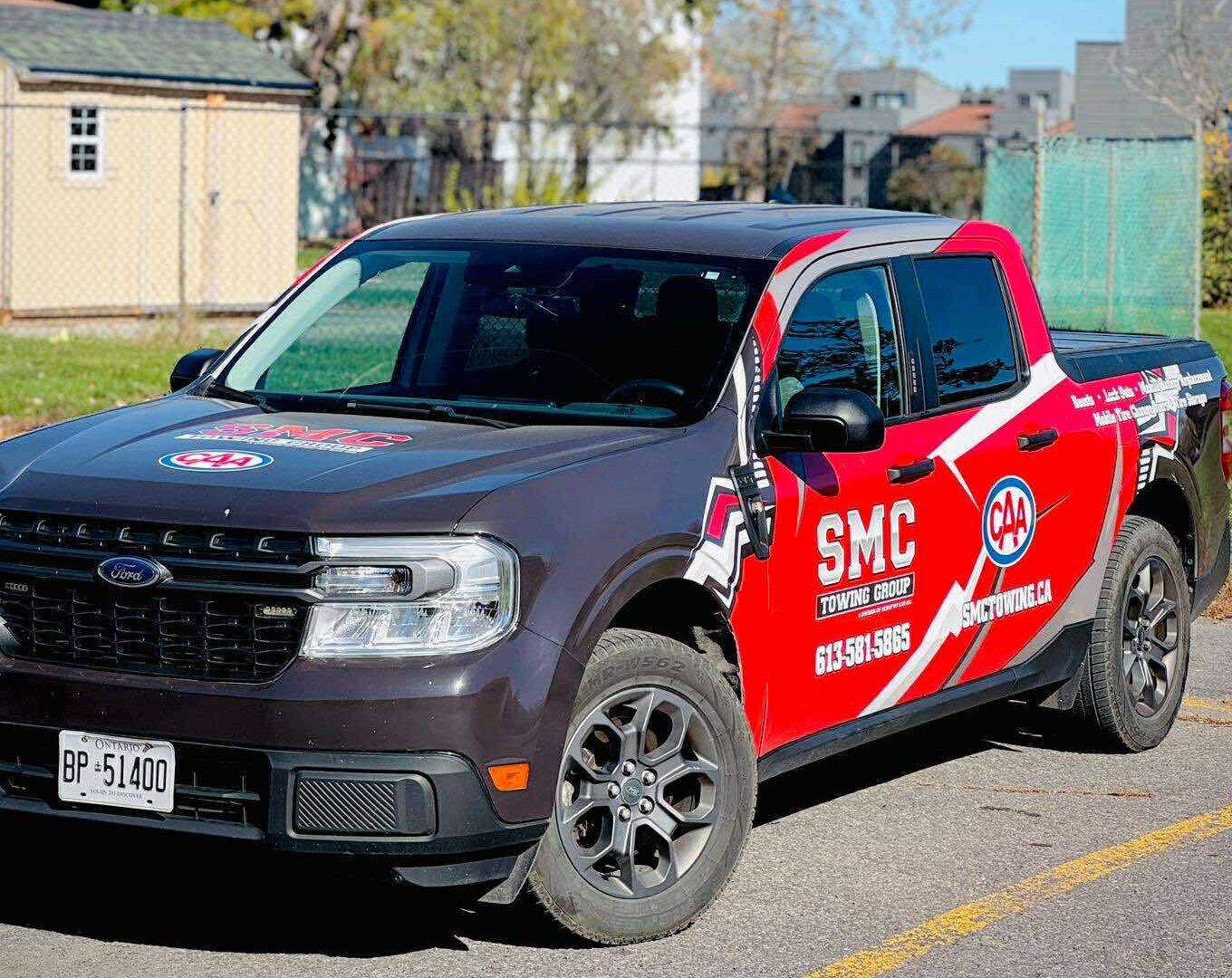 SMC Towing Group Ford pickup truck with CAA branding parked outdoors on a sunny day.