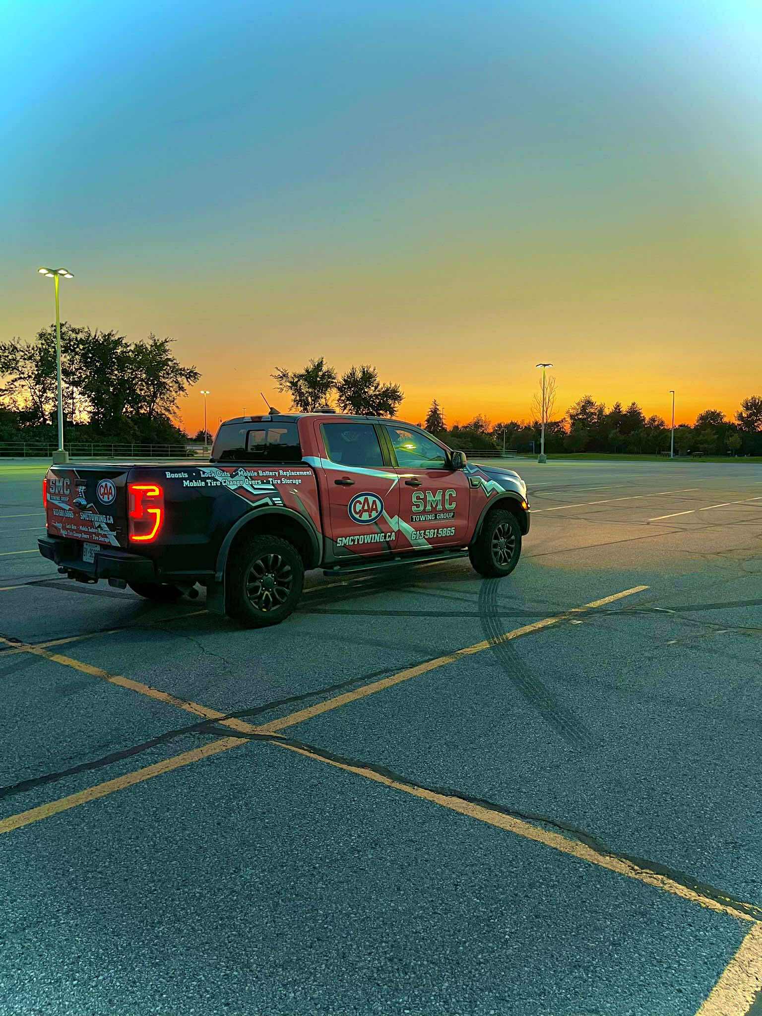SMC Towing Group pickup truck with CAA branding parked in an empty lot during sunset.